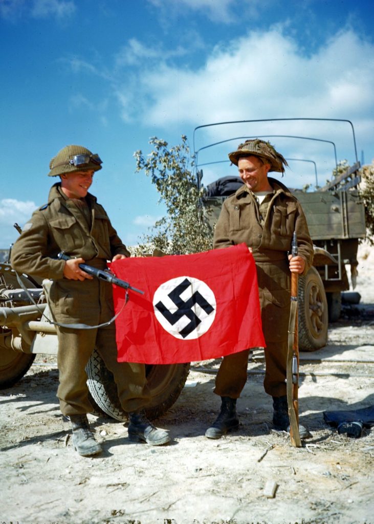 Soldiers of the Royal Canadian Army with a captured Nazi flag in Normandy