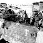 Soldiers eating rations in their Kubelwagon. Note the palm tree with swastika stencil on the door