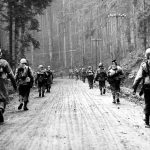 US 7th Army infantryman march through a forest, 1945