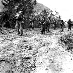An advance patrol of the 77th Infantry Division moves cautiously up a trail on Takashiki Shima, scouting an advance route for the main body that later overran the island.