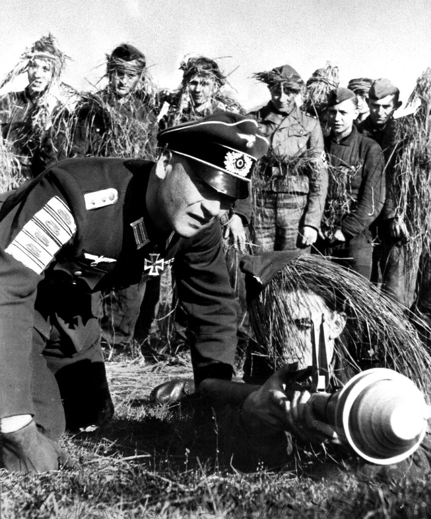 A Wehrmacht veteran teaches Hitler Youth boys how to use a Panzerfaust. The badges on his sleeve represent enemy tanks destroyed
