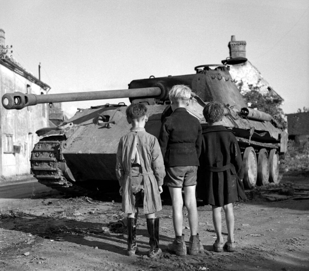 Three French boys looking at a knocked-out German Panther tank in the Falaise pocket, Normandy, 25 August 1944
