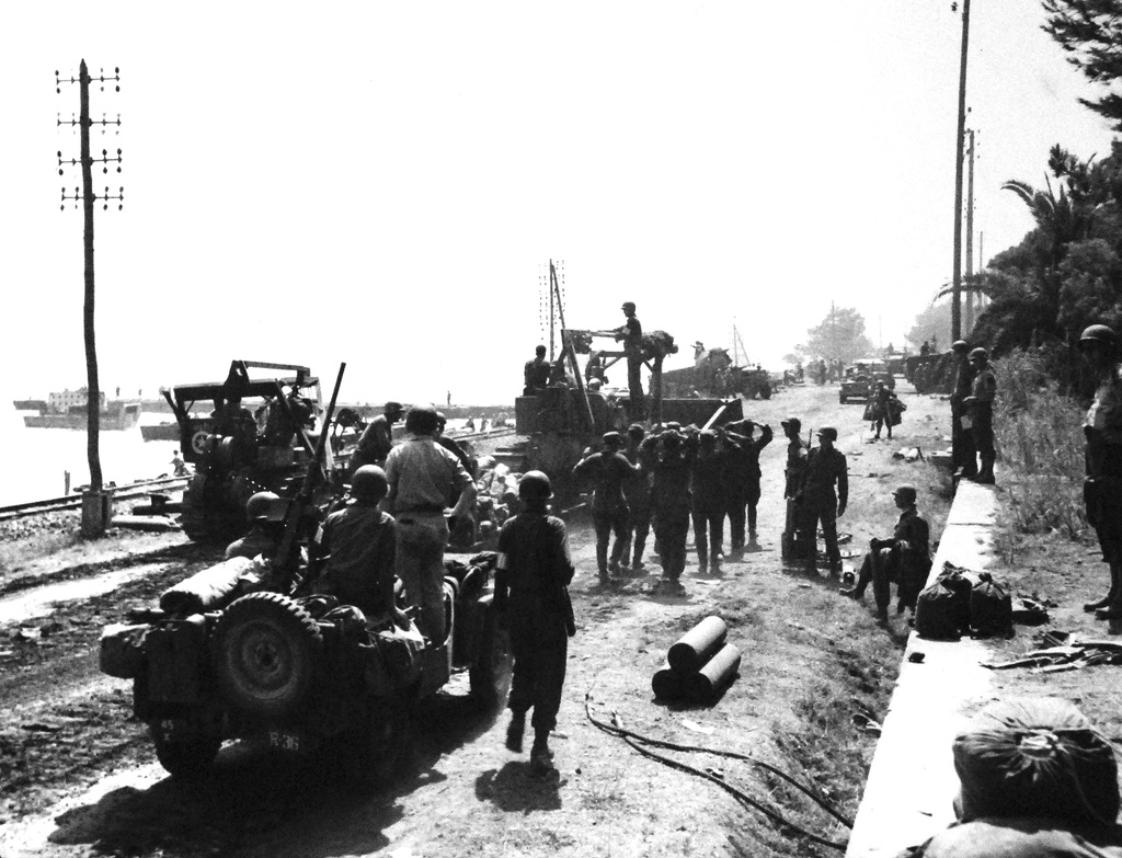 Southern France, August 1944. With hands aloft, “German” prisoners are passed to the rear under heavy guard on the beach of Southern France