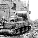 Two soldiers of the 743rd Tank Battalion, 30th Infantry Division, U.S. 9th Army, taking a break by what was a beer parlor, in Magdeburg, Germany; April 17, 1945