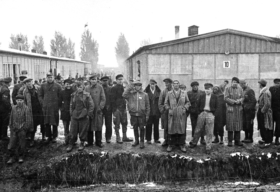Group portrait of survivors standing by moat at Dachau