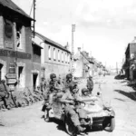 American paratroopers ride a captured Kubelwagen at the crossroads on the RN-13 in Carentan