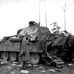 An American soldier walks by a destroyed German Befehlspanther or command Panther in France August 1944