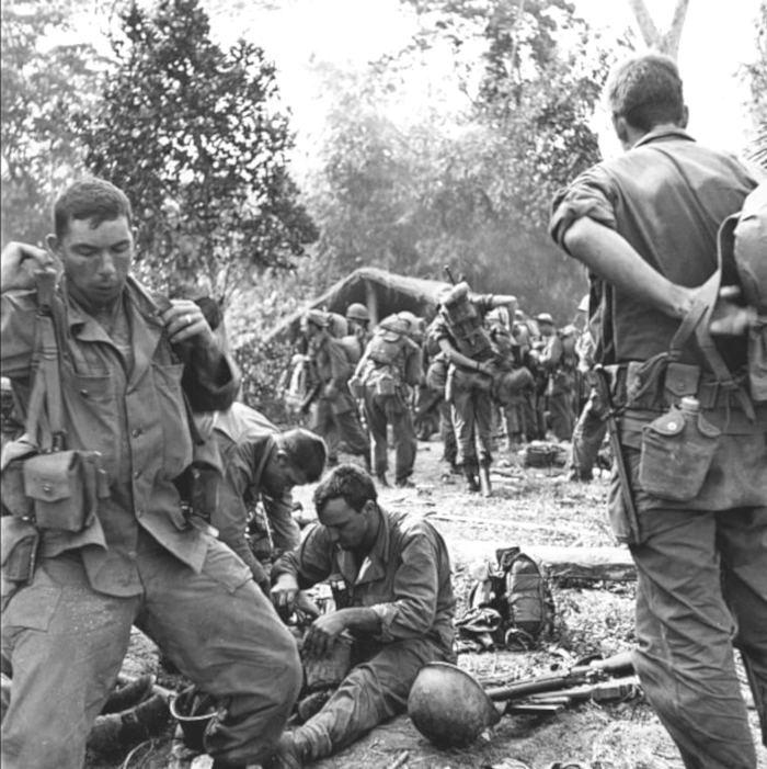 (Illustration) After four days fighting the Japanese, weary American soldiers set down their packs at a Kuchin village in the Hukawng Valley. Northern Burma, 1944