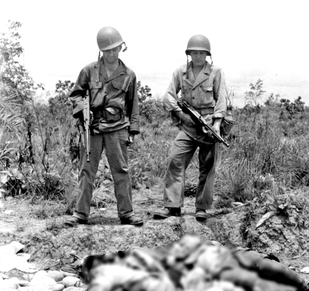 Two members of the 5307 (C)(P) Merrill's Marauders and their M-1928-A1 .45 Cal Thompson SMGs look at two fallen enemy soldiers at Myitkyina Airfield in Burma - May 1944