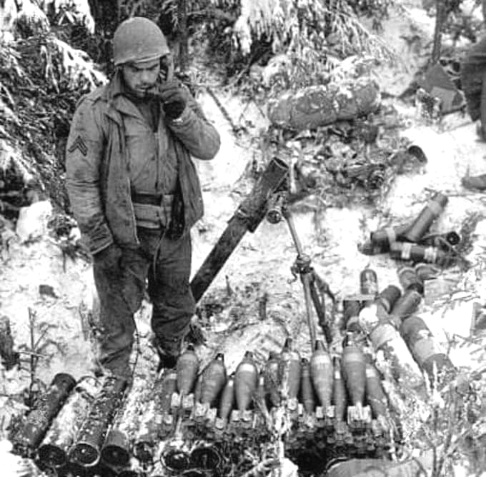 December of 1944,  a US 1st Army soldier mans an 81mm mortar while listening for fire direction on a field phone during the German Ardennes offensive