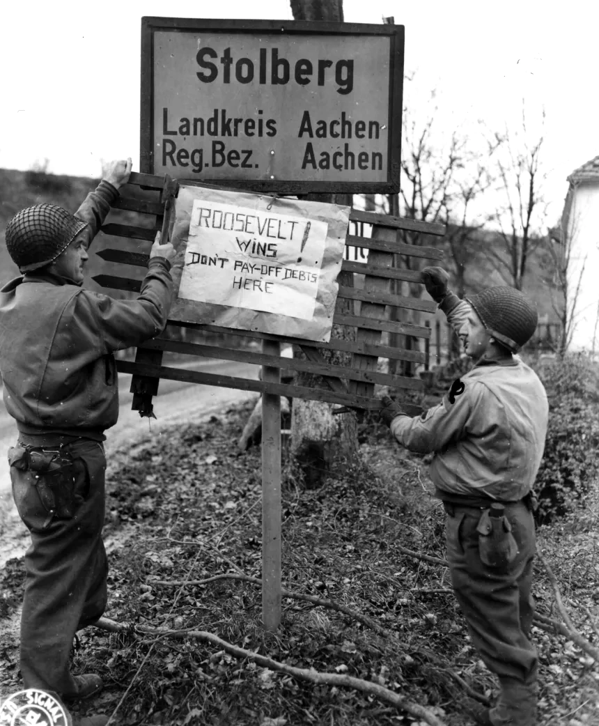 3rd Armored Division men Sgt. Arnold J. Wethingston (left) and SSgt. Kenneth R. Peterson, of Barron, Wis., posted the highlights of the recent election results on a highway intersection 3rd Armored Division men Sgt. Arnold J. Wethingston (left) and SSgt. Kenneth R. Peterson, of Barron, Wis., posted the highlights of the recent election results on a highway intersection
