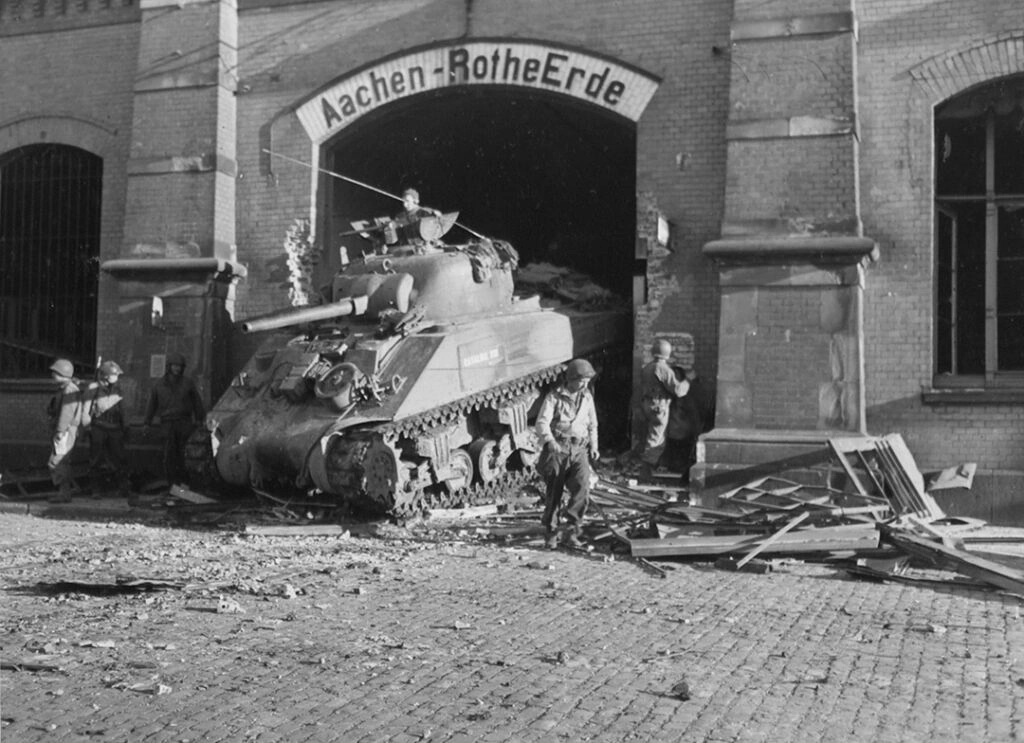 An M4 Sherman supporting the infantry during the street fighting plows through a hole in the wall of the Aachen train station An M4 Sherman supporting the infantry during the street fighting plows through a hole in the wall of the Aachen train station