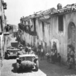 2-AD-EUCMH-Operation Husky-Sicily-1943-“1943- Natives of Pollina, Sicily, watch American soldiers and their vehicles moving along in a narrow street after the town fell to the Allies