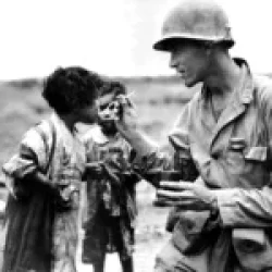 An American serviceman shares his rations with two Japanese children. Okinawa, 1945