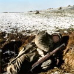 Miserable looking GI huddled in his foxhole during the Battle of the Bulge, just south of Bastogne, Belgium. December 23-26, 1944