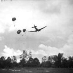 Myitkyina Task Force. C-47 plane dropping with chutes ammunition and rations for Galahad Troops in field about 1500 yards from Japanese lines. 14 July 1944