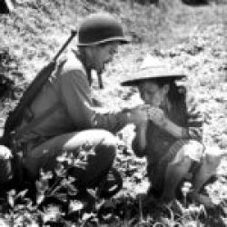 U.S. Coast Guard correspondent Victor Hayden lighting a cigarette for an Okinawan peasant woman